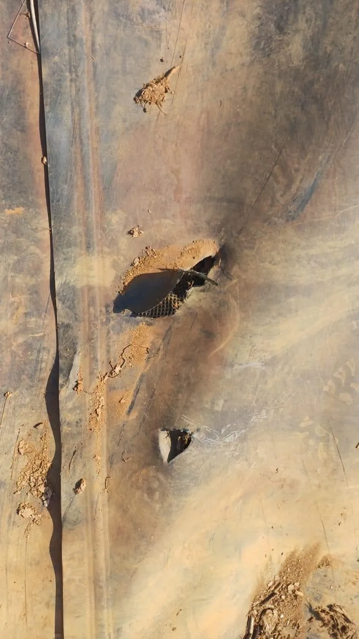 Damaged dam lining with holes and exposed reinforcement